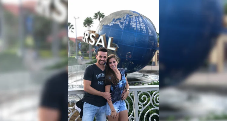 Casal na frente da Universal, onde tem a bola escrito UNIVERSAL