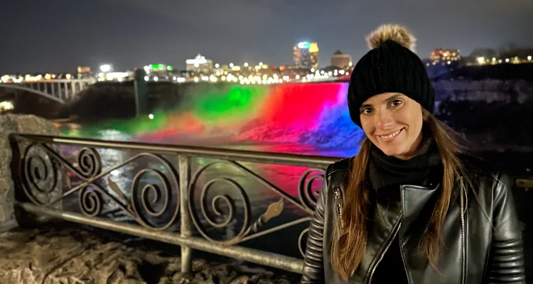 Mulher a noite com as cataratas do Niagara atras toda iluminada