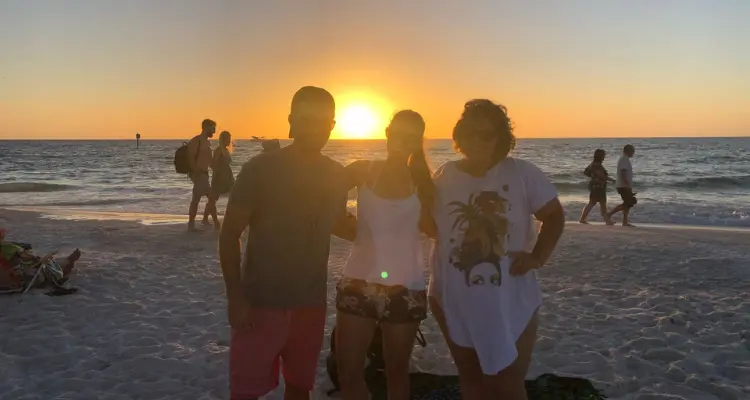 3 pessoas na praia no por do sol