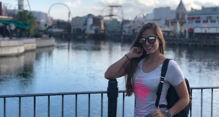 mulher em frente a uma grade com os parques de Orlando no fundo